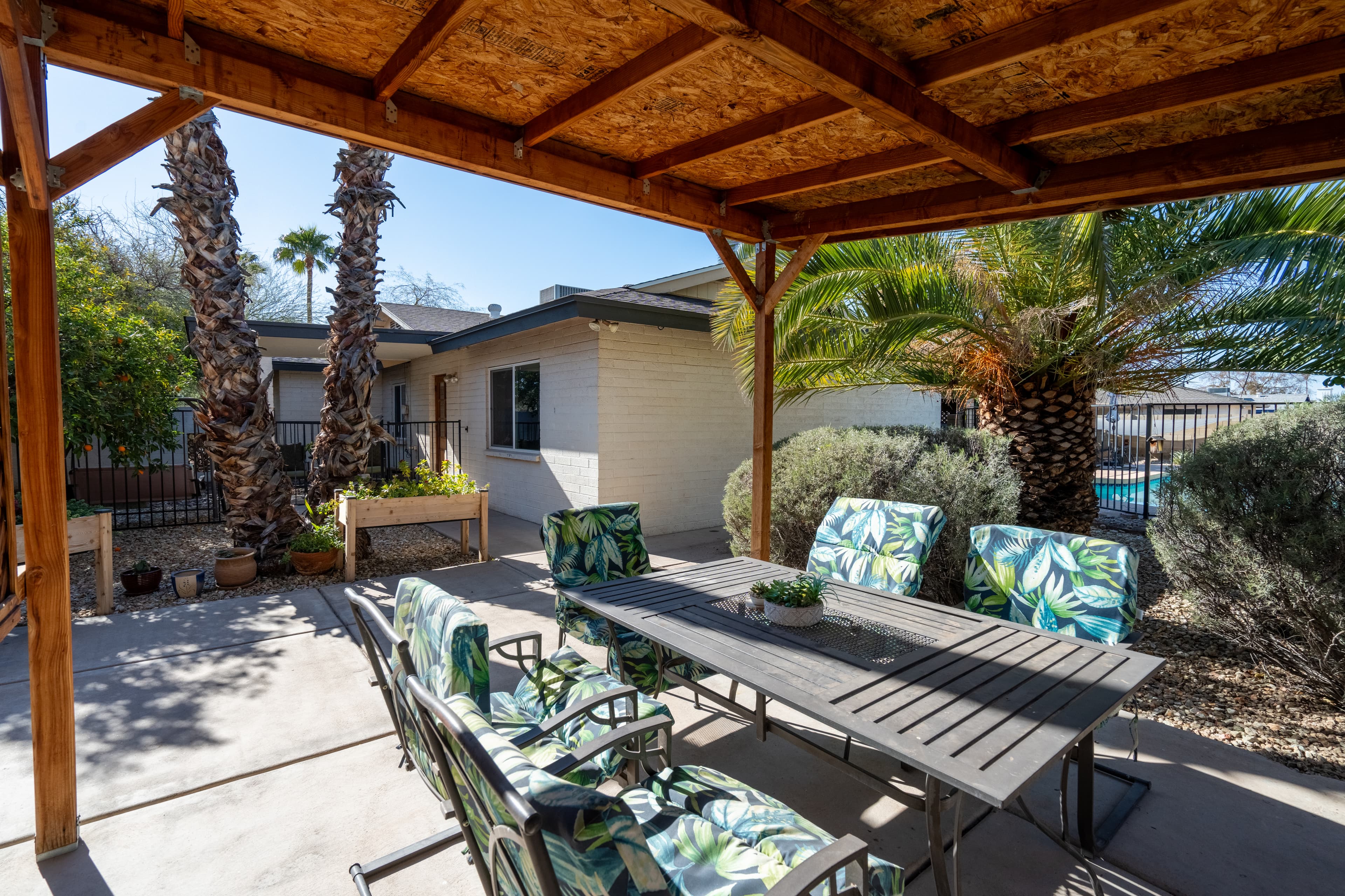 Covered outdoor patio with dining table and palm trees