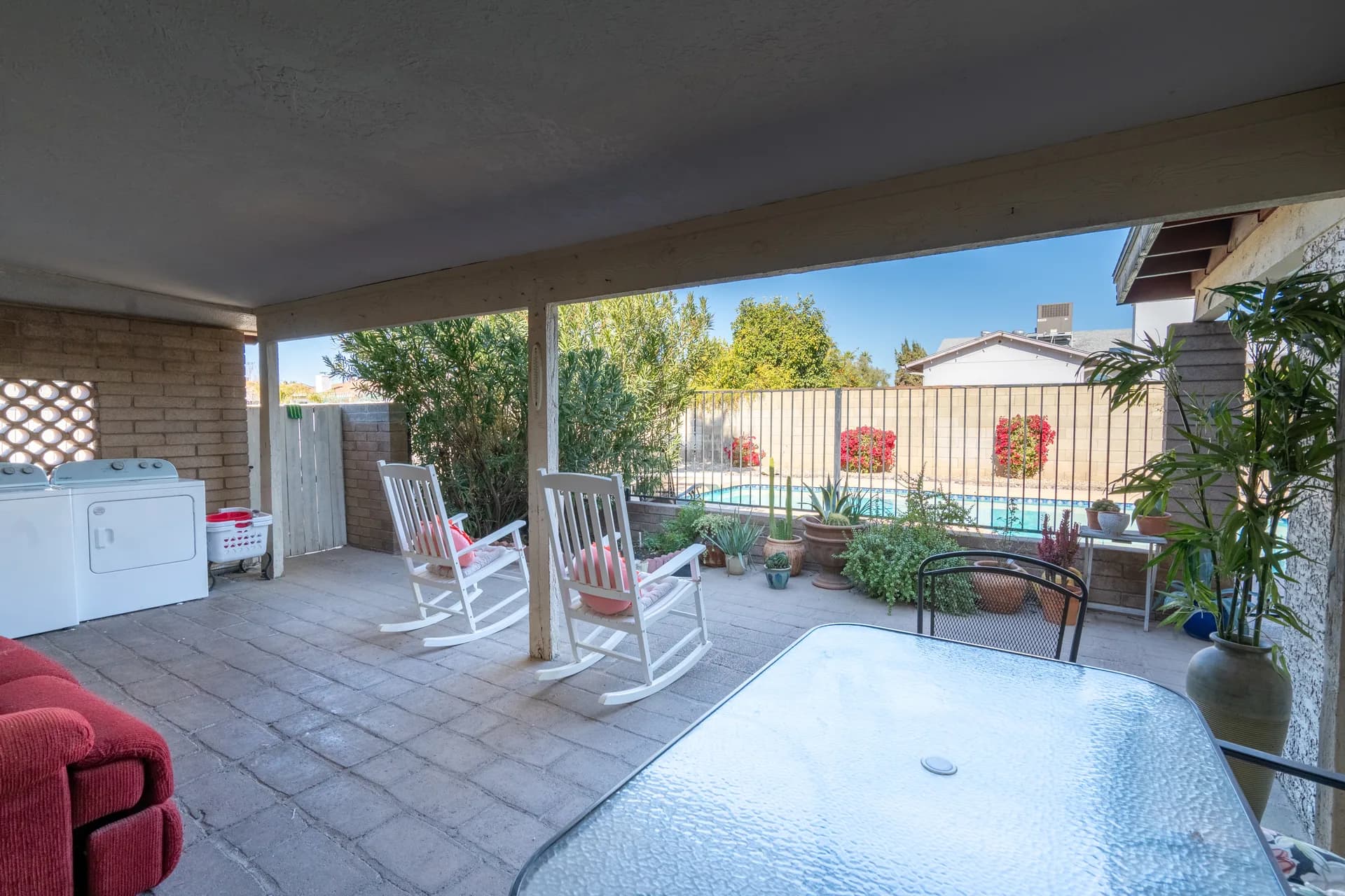 Covered back patio with rocking chairs overlooking pool